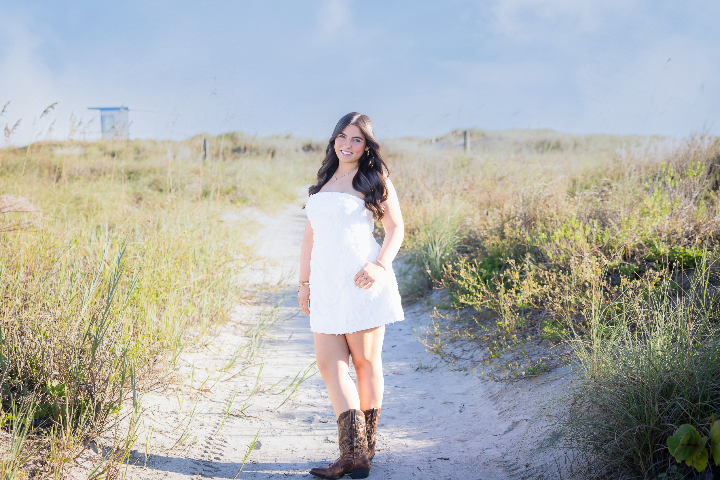 Senior girl walking along the sandy beach path through the sea oats at Jetty Park.