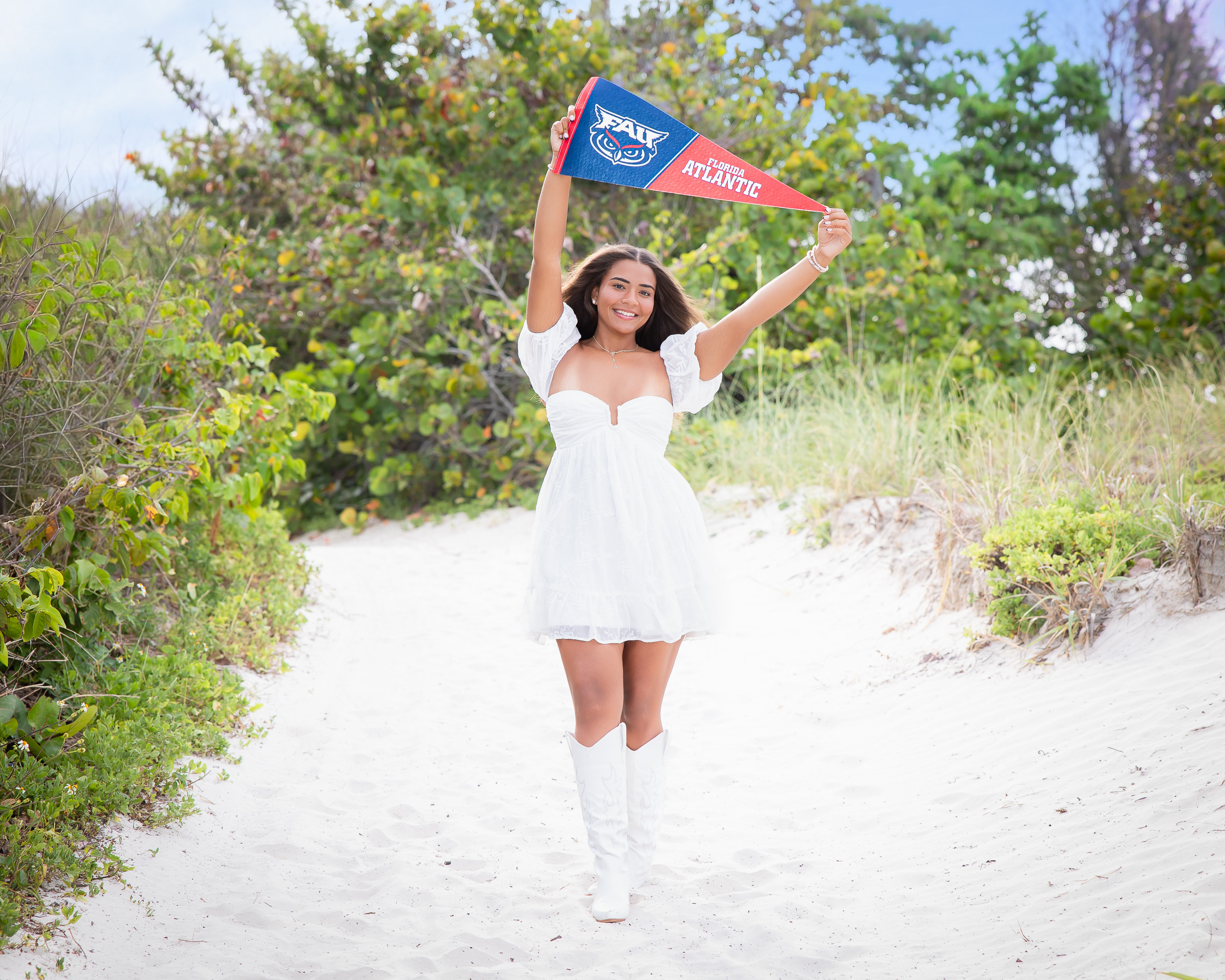 Senior girl walking along a sandy beach path at Jetty Park during a senior photo session in Cape Canaveral, Florida.