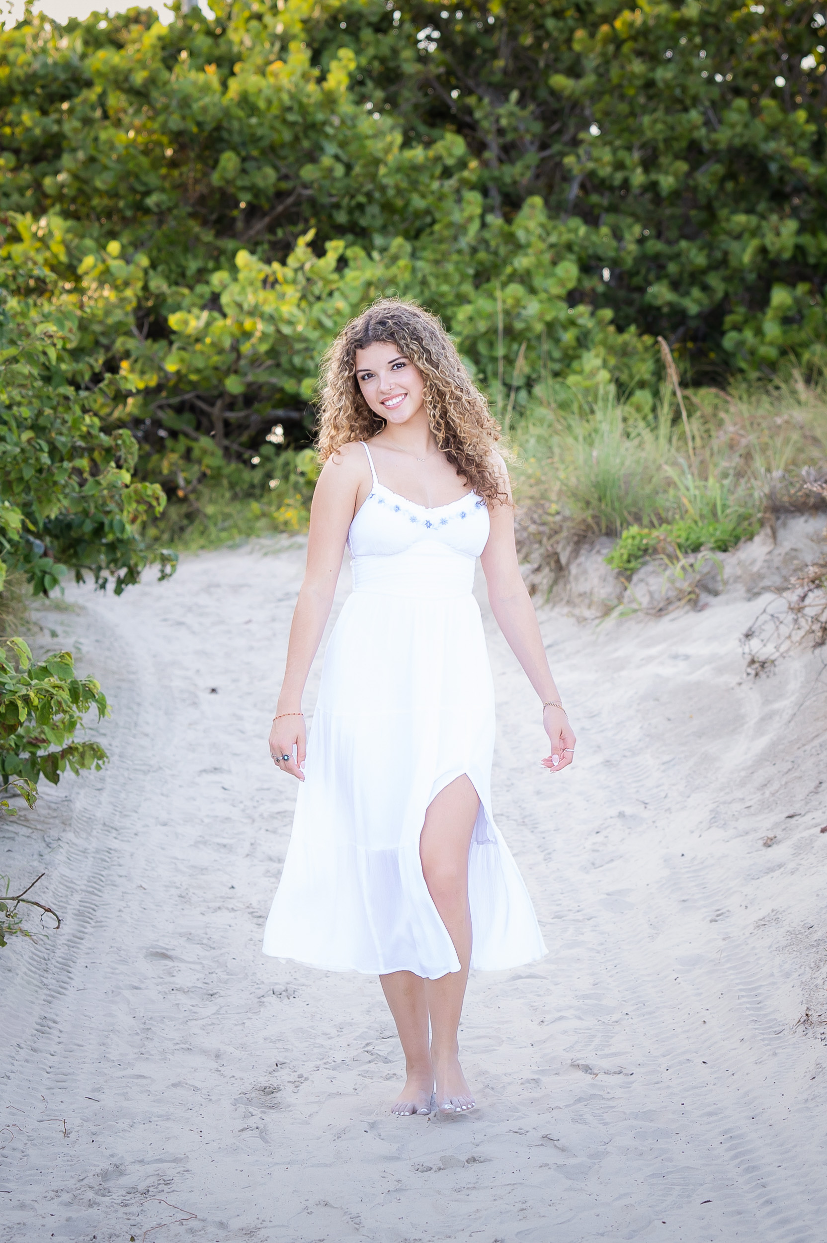 Senior girl walking along the beach path through the sea oats at Jetty Park.