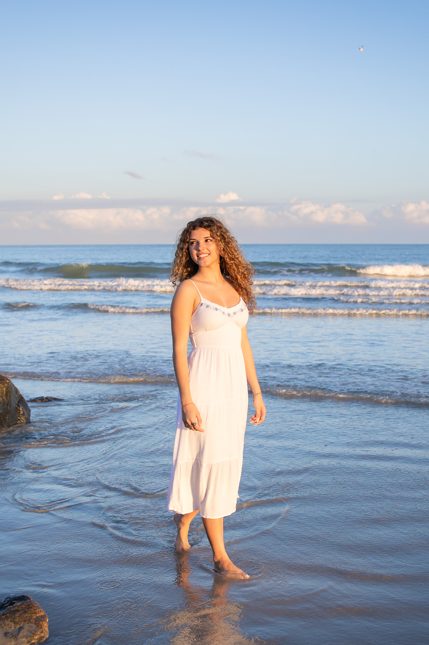 Senior girl in a white dress at sunset during a senior photography session at Jetty Park in Cape Canaveral, Florida