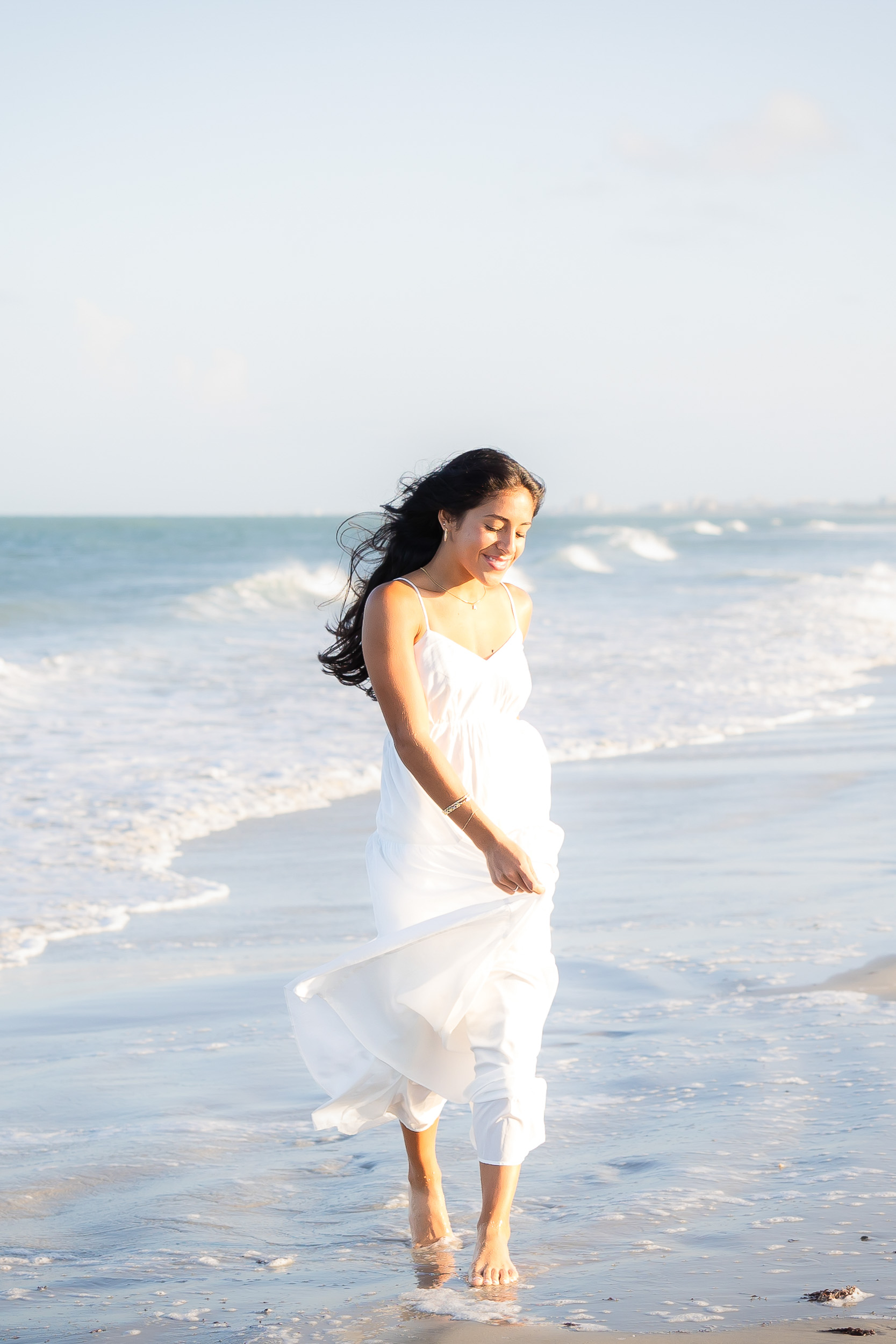 High school senior girl walking through the waves during a senior photo session at Jetty Park in Cape Canaveral, Florida.
