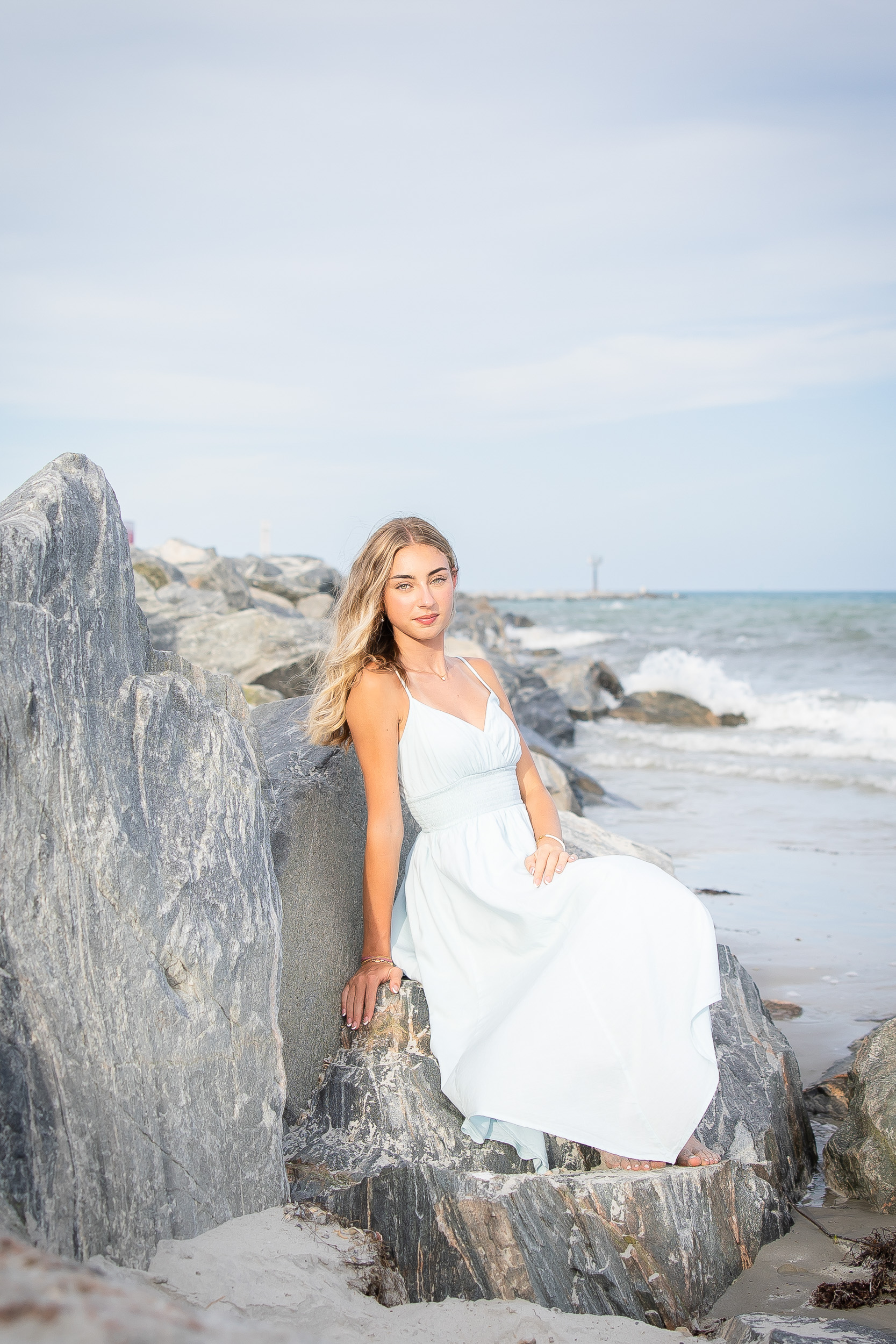 Senior girl sitting on the rock jetties at Jetty Park in Cape Canaveral during a Florida beach senior session.